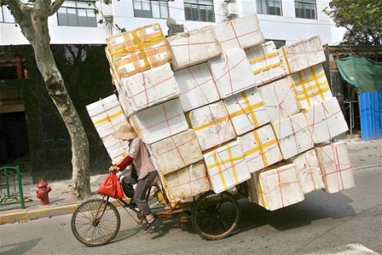 Shangai sokaklarından birinde geri dönüştürülmesi için bisikletiyle strafor taşıyan bir kadın.