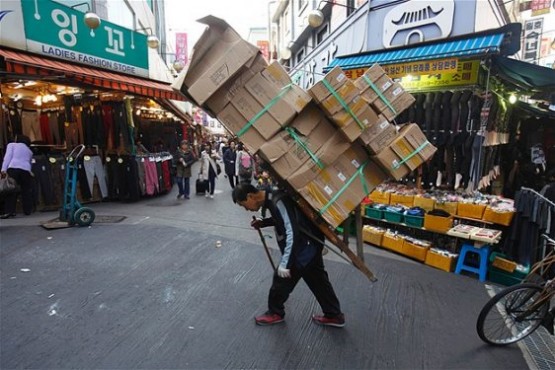 Seoul kentindeki Namdaemun pazarında sırtında onlarca kutu taşıyan adam.