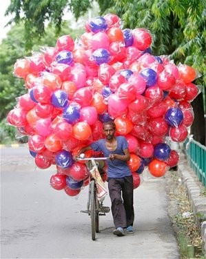 Yeni Delhi’de bir adam kullandığı bisiklette top taşıyor