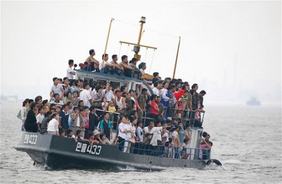 Kuzey Kore ve Çin arasından geçen Yalu Nehri boyunca süzülen aşırı yüklü bir tekne